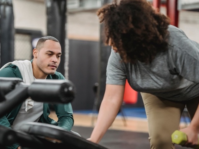 A coach watching a lifter work through a set of dumbbells.