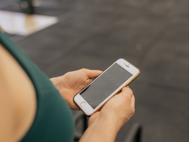 A phone held in both hands in a gym between sets.