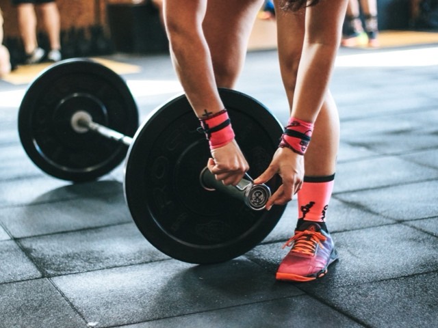 Hands tightening the collar on a loaded barbell.