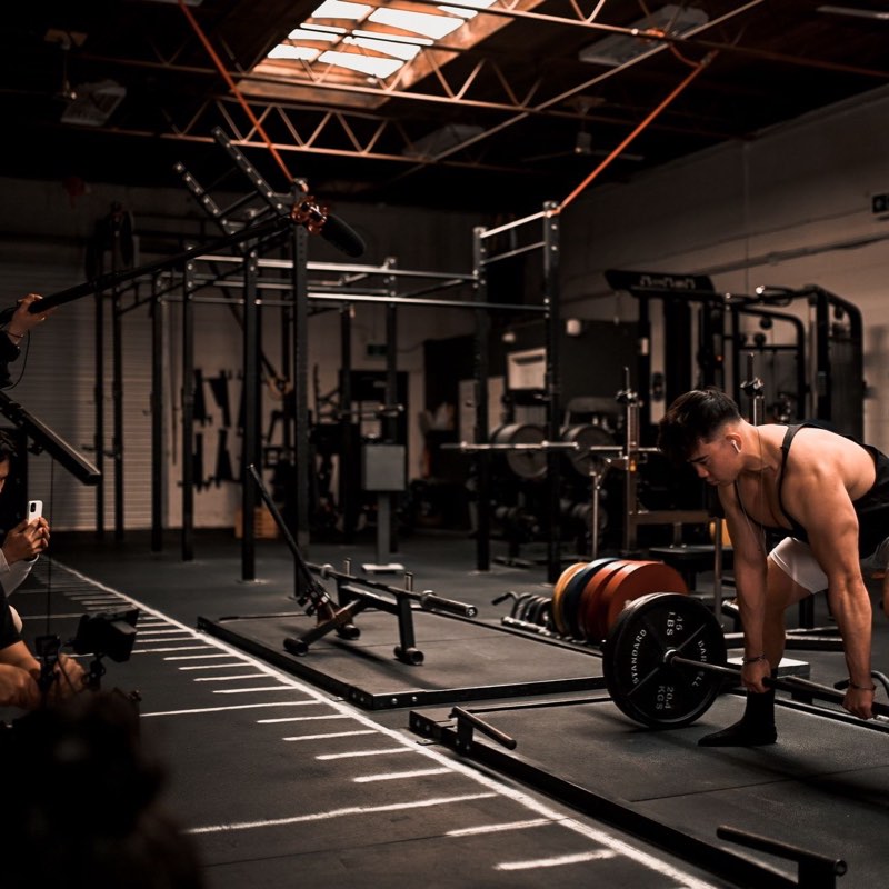 A small crew filming a lifter setting up a deadlift.